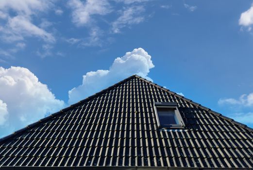 Open roof window in velux style with black roof tiles