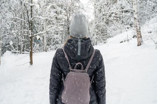 Woman in winter jacket walking in snowy winter forest, snowy winter day