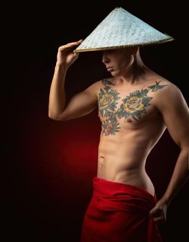 a half-naked male monk in a triangular Asian hat