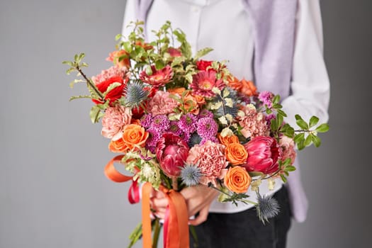 Flower arrangement in Wicker basket. Beautiful bouquet of mixed flowers in woman hand. Handsome fresh bouquet. Small flower shop and Flowers delivery