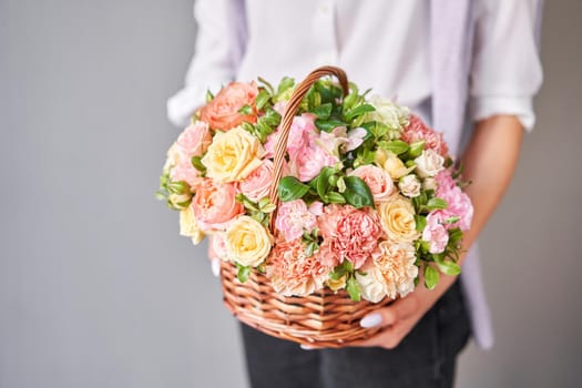 Flower arrangement in Wicker basket. Beautiful bouquet of mixed flowers in woman hand. Handsome fresh bouquet. Small flower shop and Flowers delivery