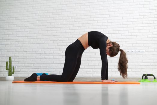girl conducts a home workout stretching to strengthen her back