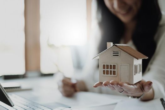 A woman holding and checking house model .Real Estate House Appraisal And Inspection and Insurance concept