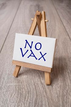 the phrase No Vax painted on a canvas placed on a wooden easel