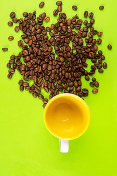 coffee beans on a yellow surface and a colored cup