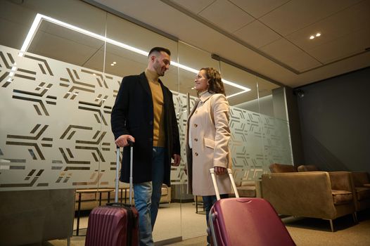 Multiracial beautiful couple in love, business partners on business trip, standing at the exit of VIP meeting room in the airport departure terminal, waiting for flight. Newlyweds on their honeymoon