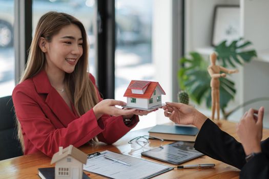 Real estate agent sales manager holding house model to customer after signing rental lease contract of sale purchase agreement, concerning mortgage loan offer for and house insurance.