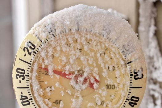 Close up of a Frosty snow-capped outdoor Thermometer on a frigid cold winter day. Temperature reads minus 26 degrees Celsius or minus 16 Fahrenheit