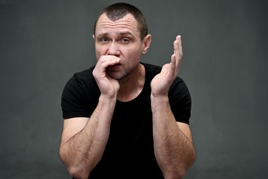 Close-up portrait of a man shouting into his hand on a gray background