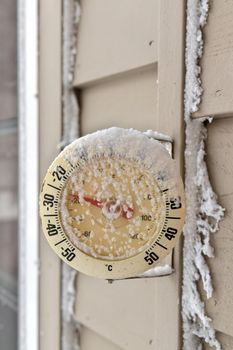 Close up of a Frosty snow-capped outdoor Thermometer on a frigid cold winter day. Temperature reads minus 26 degrees Celsius or minus 16 Fahrenheit