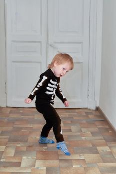 A child in a skeleton costume is dancing in the hallway of the house. Children outdoor games at home