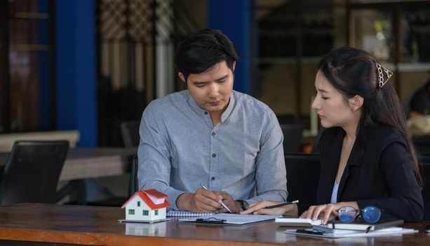 Real estate agent sales manager holding house model to customer after signing rental lease contract of sale purchase agreement, concerning mortgage loan offer for and house insurance.