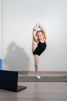 online rhythmic gymnastics. girl preschooler doing rhythmic gymnastics with a trainer online