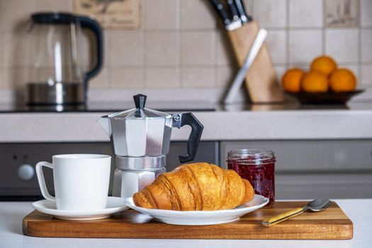 Serve on serving board with coffee, French croissant and jam in kitchen. Breakfast. Coffee is brewed in traditional Italian geyser coffee maker. Selective focus.