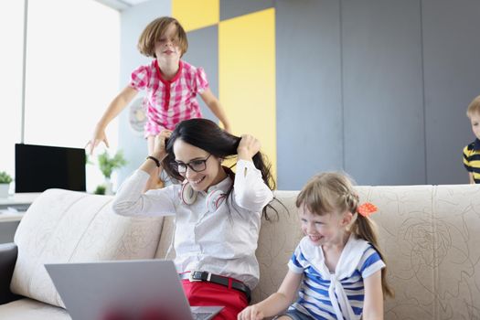 Portrait of happy woman working and playing with her kids on couch. Mother work from home, earn money for children. Parenthood, weekend, childhood concept
