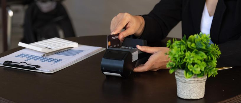 businesswoman hand pushing the button and swipe credit on terminal standing in shopping mall. shopping and retail concept.