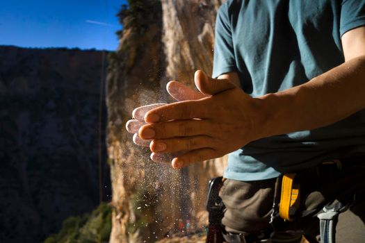 Male hands with magnesia powder close-up against the background of the mountains on a sunny day, the hands of a climber who prepares for outdoor training, a man is engaged in active sports in Greece.