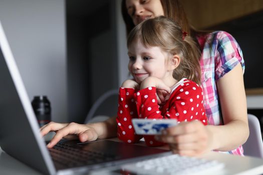 Portrait of mother buying present for daughter online via internet, happy kid waiting. Online shopping, purchase, technology, contactless payment concept