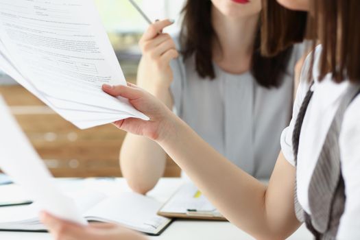 Close-up of business consultant showing business graphic report to colleague. Coworkers discuss working moments, share ideas in office. Business concept