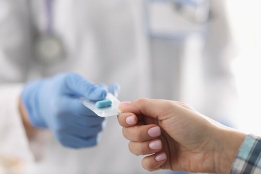 Close-up of female doctor in uniform give tablets in blister to patient. Qualified specialist advice drug for treatment. Medicine, pharmacy, cure concept