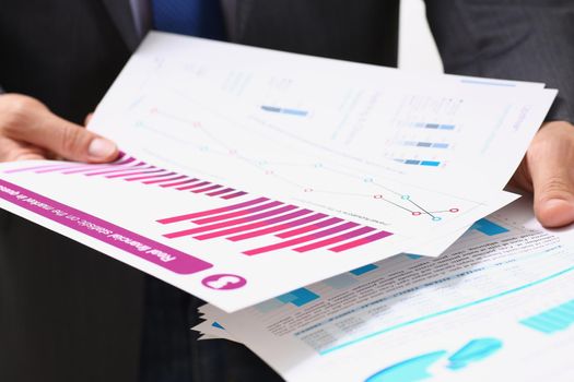 Close-up of businessman in suit holding agreement form or annual report in finance. Team leader, business, career, development, economy, growth concept