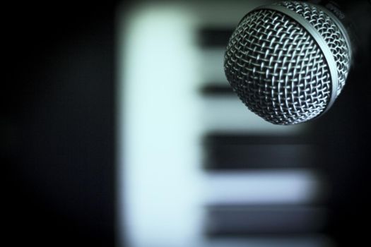 Microphone over piano keys in dim light. No people