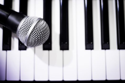 Microphone over piano keys in dim light. No people