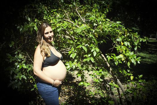 Seven month pregnant woman in a park dressed in jeans