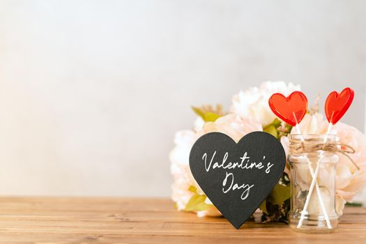 Valentines day festive background with empty black chalkboard heart and 2 lollipop on wooden background. Mockup with copy space for design.