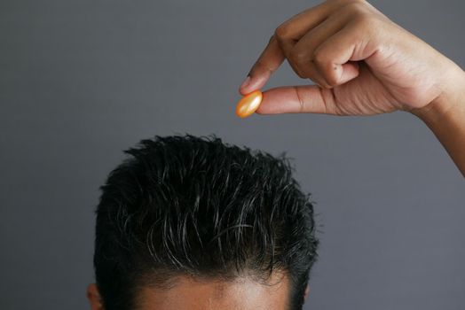 men applying capsule oil on hair .