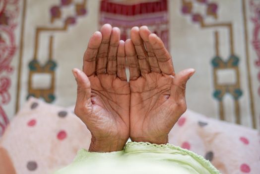 Close up of senior women hand praying at ramadan .