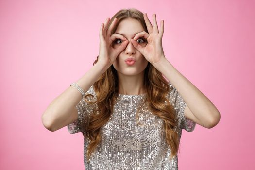 Funny cute attractive european young woman not afraid be immature playful folding lips silly show glasses make goggles using hands fooling around mimicking pilot, standing happy pink background.