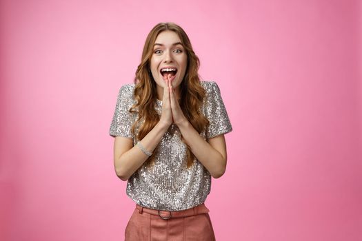 Excited attractive girlfriend eager start pack ready travel abroad win tickets press palms together happily thrilled looking amused feeling happiness standing pink background glamour outfit.