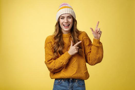 Carefree friendly nice flirty stylish woman wearing sweater hat laughing joyfully enjoying funny company joking pointing upper right corner index fingers delighted, showing cool promotion.