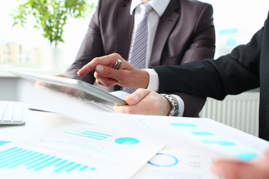 Two businessmen looking and studying analytics and business statistics. Colleague points out problem to partner in business report concept