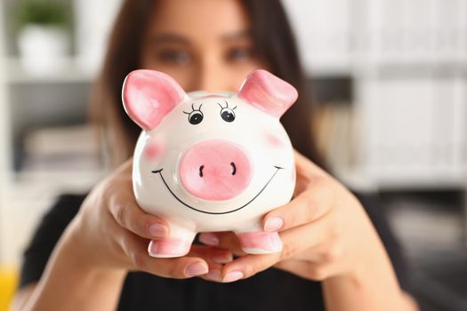 Young woman holding piggy bank in hands pink pig piggy bank. Accumulation of funds concept