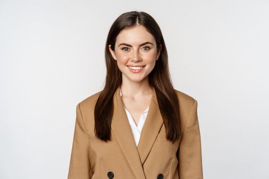 Portrait of business woman with enthusiastic face expression, smiling, looking confident, standing in suit over white background.