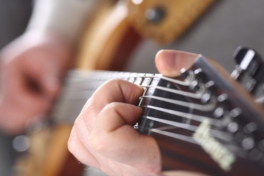 Male hands holding and playing wooden guitar. Six string training guitar and music school concept