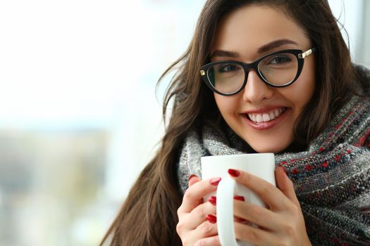 Beautiful girl is holding large cup in hands. Seasonal cooling and positive mood concept