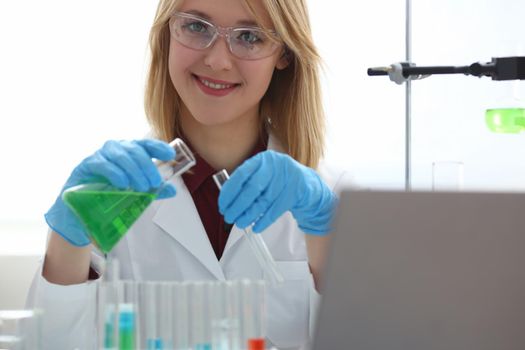 Scientist holds bottle with sample with toxic green liquid in hands in protective gloves. Toxic substances and liquids concept