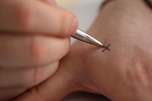 Man makes x note with cross with pen on hand, closeup. Try not to forget to do list concept