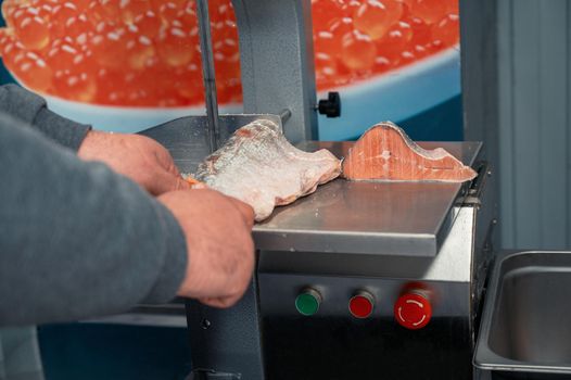 Service for cutting frozen salmon fish on a steak in a fish supermarket using professional equipment