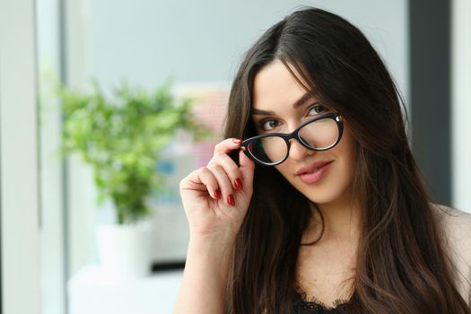 Beautiful smiling fashionable businesswoman holds glasses in hand and looks into camera. Business consultant concept