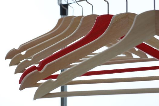 Red and wooden hanger hanging from metal pipe. Business leader selling clothes and style concept