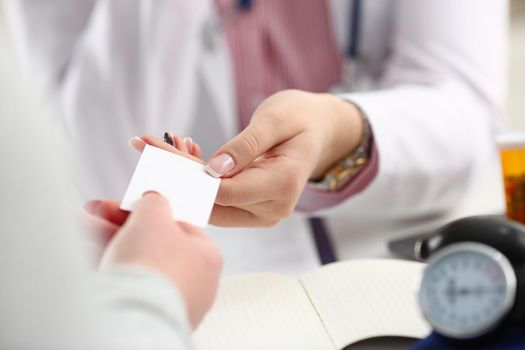 Female doctor hands over white business card to patient. Attending physician choice concept