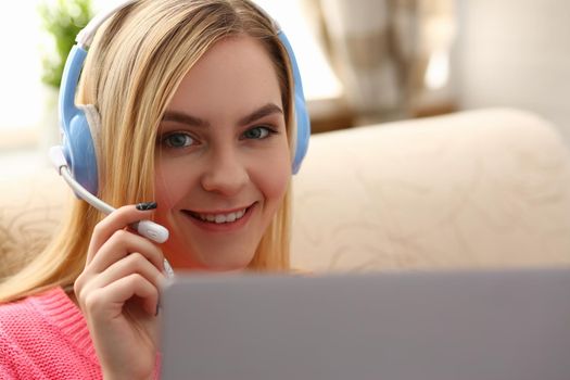 Portrait of happy young caucasian woman in headphones talking online with client via digital webcam. Remote communication concept