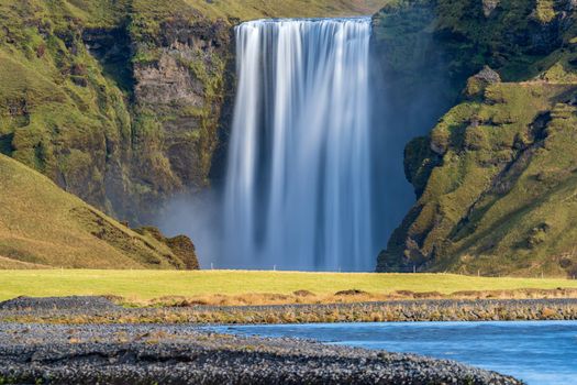 Long exposure of Skogafoss waterfall in Iceland from the distance river and no people