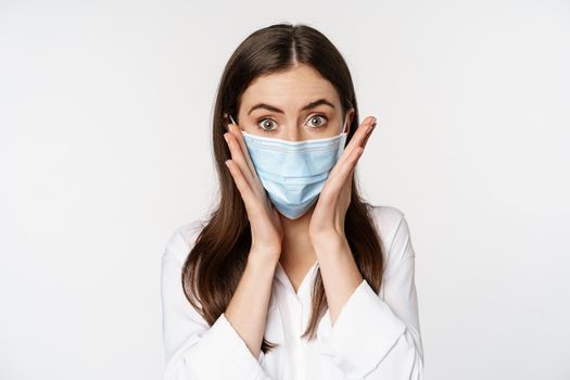 Covid-19 and pandemic concept. Young office woman wearing medical mask during coronavirus social distancing, standing over white background.