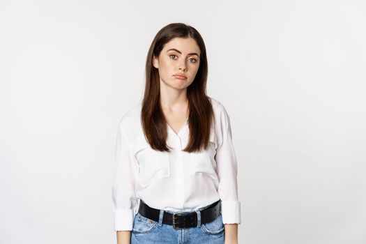 Sad and gloomy woman sulking, looking disappointed and moody, standing upset against white background.