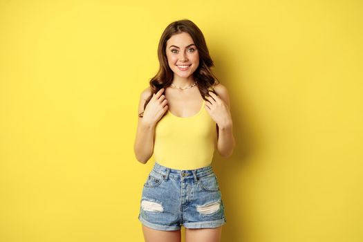 Portrait of enthusiastic, hopeful woman looking with yearning, smiling happy face, expecting smth, desire, standing over yellow background.